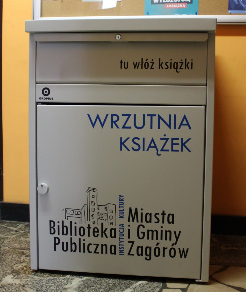 Na zdjęciu wrzutnia do książek oznaczona logo biblioteki i opisana. W górnej części szuflada z napisem : tu włóż książki 